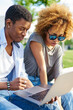 © BullRun - African american couple in love watching online tutorial on modern laptop computer using public 4G internet in urban setting.Dark skinned young man and woman doing shopping in webstore on netbook