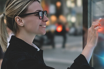 Wall Mural - smiling female standing at big display with advanced digital technology. young woman touching with f