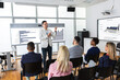 © Mediteraneo - Male CEO standing in front of a multiracial group of colleagues. Multimedia classroom with smart board and graphics on them.