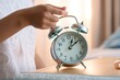 © alisaaa - close-up hand of teenager girl stopping alarm clock on the bed in the morning. woman sleeping in bed and alarm-clock