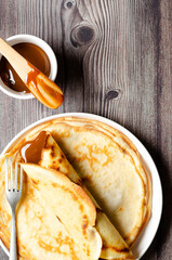 argentinian crepe filled with dulce de leche and a bowl of dulce de leche on wooden background.