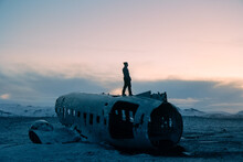 Solitary Figure Stands Atop Plane Wreckage In Snowy Iceland