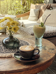 Wall Mural - A cup of coffee with latte art on top on wooden table with  mango smoothie