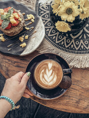 Wall Mural - A cup of coffee with latte art on top on wooden table with  pancakes