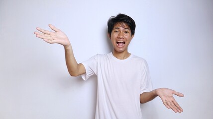 Wall Mural - Excited young Asian man in white shirt gestures with open arms