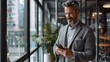 © KPN Photo - A handsome businessman smiling while talking on the phone in an office, sitting at a desk with a laptop, tablet, and computer, looking professional and engaged in communication