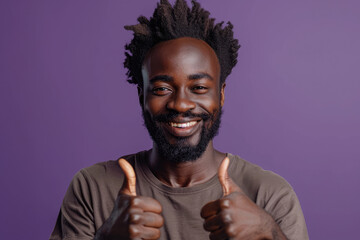 Wall Mural - Photo of a happy black man wearing a casual t-shirt showing thumbs up on a purple studio background