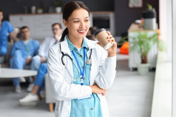 Poster - Female Asian doctor with coffee cup in hospital rest room