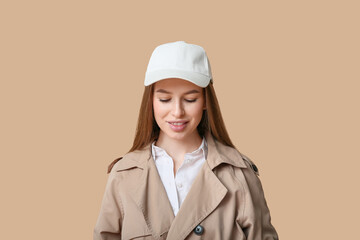 Beautiful young woman in stylish white cap on brown background