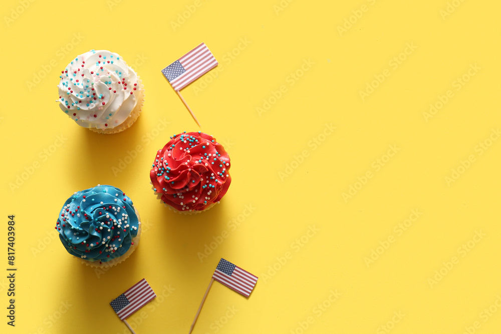 Tasty patriotic cupcakes with USA flags on yellow background. American Independence Day