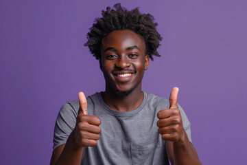 Wall Mural - Photo of a happy black man wearing a casual t-shirt showing thumbs up on a purple studio background