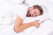 © be free - Yawning early in the morning. Asleep young man sleeping. Resting peacefully in comfortable bed. Lying with closed eyes. Man sleeping at night. Sleepy man lying on bed sleeping at white bedroom