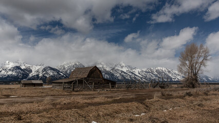 Old barn with Teton range in background with wispy clouds and blue sky