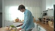 © InfiniteFlow - Happy father move to music while cooking food and prepare lunch at modern kitchen. Active dad dancing to song while making healthy food or salad surrounded with vegetable and kitchenware. Pedagogy.
