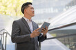 © Naypong Studio - Professional businessman using tablet outdoors