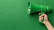 © Wall - A hand holds a green megaphone near a green wall Another hand, also holding a green megaphone, is attached to it, as if passing it on
