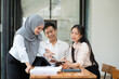 © aekachai - Group of Asian business people planning a project, discussing work documents.