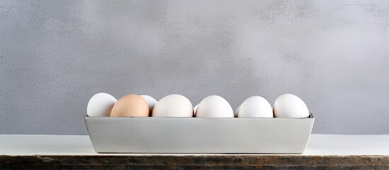 Wall Mural - A container with white colored eggs on a concrete background providing ample copy space for additional images or text