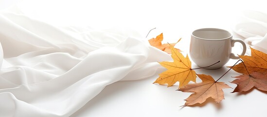 Poster - Autumn leaves on a white background complemented by a cup of coffee and a cozy green blanket Copy space image