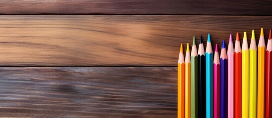 Aufkleber - A colorful arrangement of pencils on a wooden background creating a back to school theme with copy space image