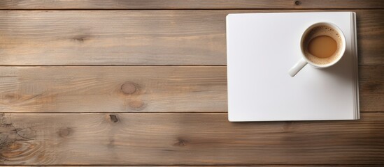 Poster - On a wooden table there is a cup of coffee and a notepad with ample copy space image