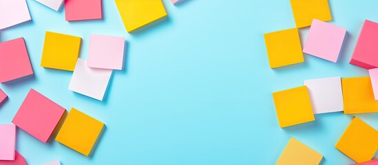 Leinwandbilder - Plenty of yellow and pink square blank paper stickers scattered on a vibrant blue background providing ample copy space Top view