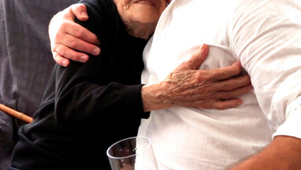 An elderly hundred-year-old man, grandmother, tightly hugs a middle-aged man with wrinkled arms. tenderness and trust between generations