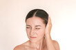© Ольга Шефер - Young caucasian brunette woman is experiencing acute pain in her ear. She presses her ear with her hand, suffering from otitis. Isolated on a beige background