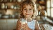 © tanongsak - A blond child smiling while holding a glass of milk.