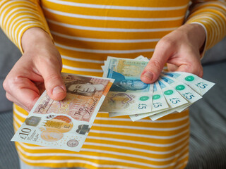 Close up of hands paying out cash money in UK banknotes