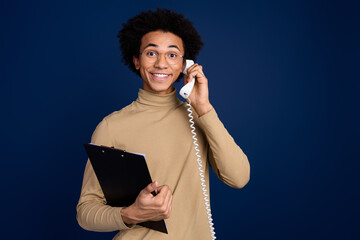 Canvas Print - Photo portrait of attractive young man hold documents talk phone dressed stylish beige clothes isolated on dark blue color background