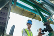 © ultramansk - Male engineer monitoring machinery on a rooftop with city skyline in the background, wearing safety gear