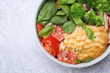 Wall Mural - Healthy meal. Delicious chicken, vegetables and spinach in bowl on light grey table, top view. Space for text