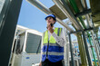 © ultramansk - Industrial engineer adjusting pipeline valve with radio communication on construction site. Engineer on urban construction site using radio to coordinate with team on a sunny industrial rooftop.