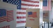 © vesperstock - Wide view, row of voting booths at polling station in United States. US flag on back wall