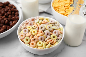 Different delicious breakfast cereals and milk on white marble table, closeup