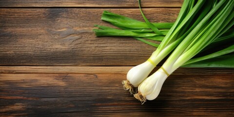 Wall Mural - Two green onions are on a wooden table. The onions are fresh and ready to be used in a meal