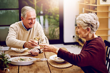 Wall Mural - Senior couple, wine and cheers on table to celebrate anniversary date, dinner or lunch at home. Happy, smile and elderly man or woman in marriage, conversation with supper and together for love