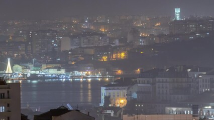 Canvas Print - Aerial view of Lisboa downtown night timelapse. Panoramic of Baixa, Rossio and Chiado rooftops from above. Illuminated buildings. Almada on the other side of Tejo river. Portugal