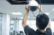© justjupiter - A technician installing a sophisticated surveillance camera system in a corporate office