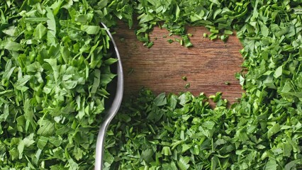 Canvas Print - Chef spoons green fresh chopped parsley to prepare a healthy meal, top view. Close-up of food