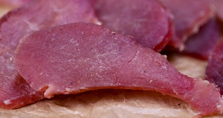 Wall Mural - dried meat on paper in close-up, pieces of dried pork with spices and salt on crumpled paper