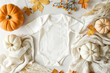 © Yuliya - Fall white cotton baby bodysuit with autumn pumpkins and leaves and beige linen fabric on a white background with copy space, autumn pregnancy announcement mockup template, Generative AI