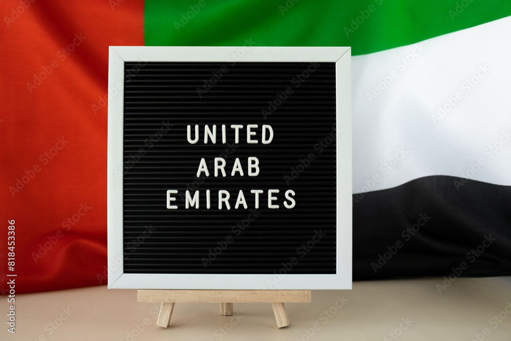 Text UNITED ARAB EMIRATES on background waving flag of UAE. National ...
