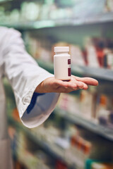 Poster - Pharmacist, hand and bottle for pills in store with by shelf for stock, show and inventory for wellness. Person, employee and container with pharmaceutical, review and presentation for drugs at shop