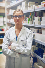 Poster - Serious, pharmacist or portrait of woman with arms crossed in healthcare clinic, pharmacy or drugstore. Proud, wellness or confident doctor by shelf for medication, pills or medicine ready to help