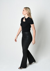 Sticker - Full length portrait of beautiful blonde woman wearing modern black shirt and leather pants. Confident standing pose with gestural hands presenting, silhouetted on white studio background.