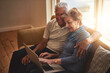 © peopleimages.com - Senior, happy couple and sofa with laptop in browsing, online shopping or financial discussion at home. Elderly man and woman discussing retirement or pension fund on computer in living room at house