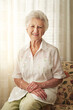 © peopleimages.com - Happy, sofa and portrait of senior woman in retirement home with cheerful, joy and smile in house. Window, living room and elderly person on weekend with confidence, calm and relaxing in morning
