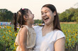 © boonroong - Asia mother and daughter laughing and smiling happily in a field of sunflowers.